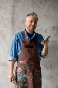 happy-and-successful-painter-with-smartphone-and-paintbrush